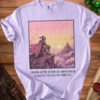 Purple t-shirt with knight on cliff overlooking castle at sunset and text.