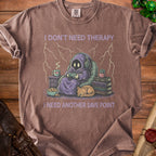 Brown t-shirt with graphic of hooded figure playing video games, text "I don't need therapy I need another save point".
