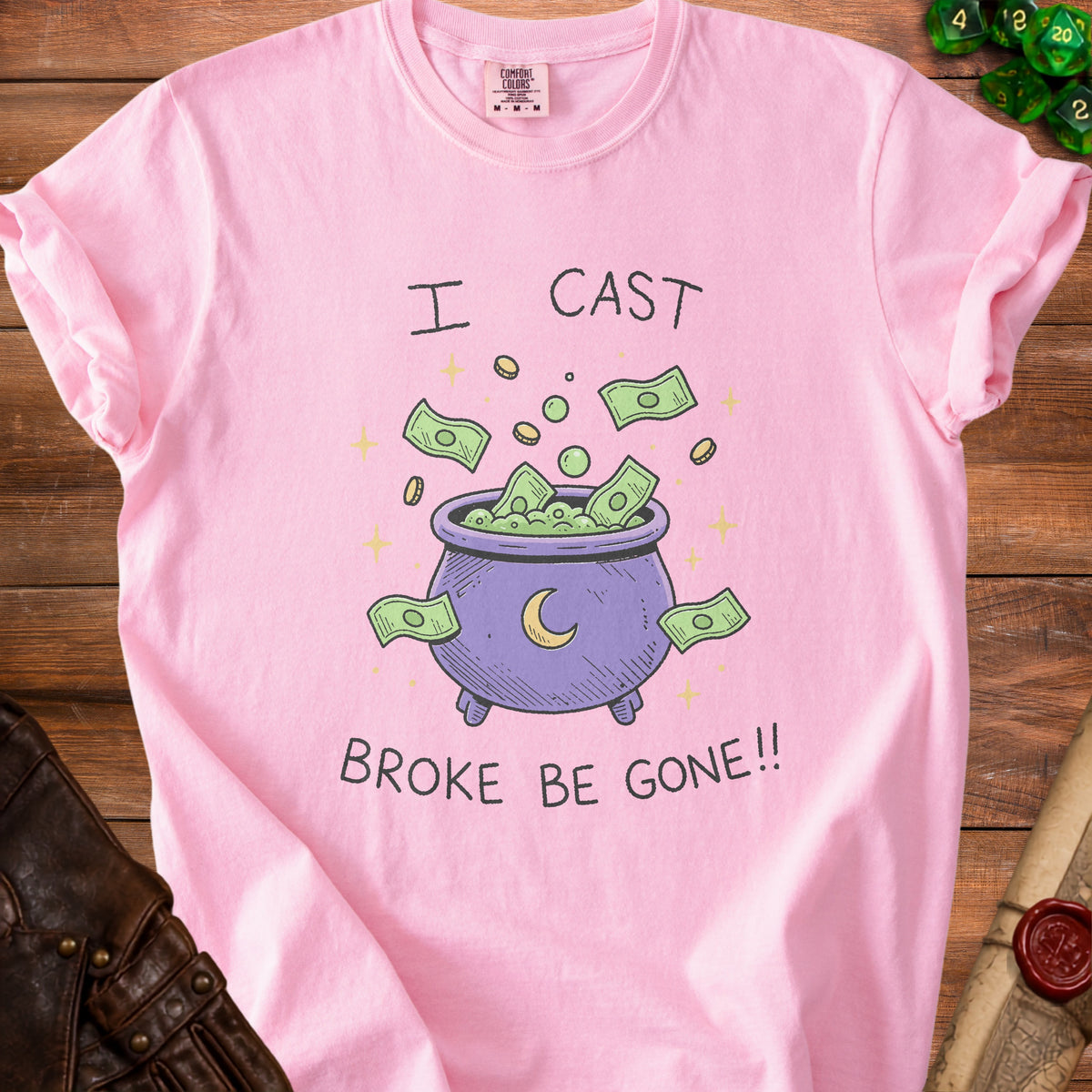 Pink t-shirt with "I CAST BROKE BE GONE!!" graphic featuring a cauldron with money.