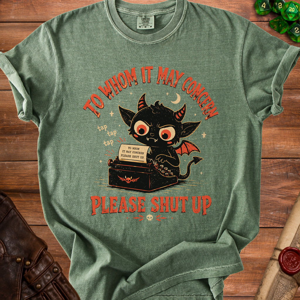 Green t-shirt with black demon typing on a vintage typewriter, reading "To Whom It May Concern Please Shut Up."