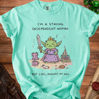 Green t-shirt with illustration of a goblin princess holding a sword and text "I'm a strong independent woman, but like, against my will."
