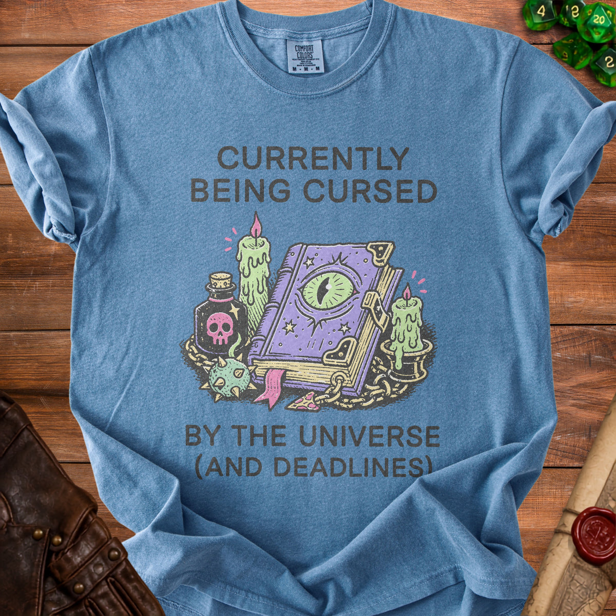 Blue t-shirt with "Currently Being Cursed By The Universe (And Deadlines)" text and wizard book graphic.