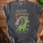Skeleton riding a dinosaur with "Socially Exhausted But Still Here" text.