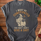 Dark gray t-shirt with a wizard on a toilet reading and the text "I MUST BE CONSTIPATED THE WAY I DON'T GIVE A SHIT".