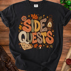 Black t-shirt with "SIDE QUESTS" text, autumn leaves, dice, and map graphics.