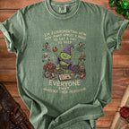 Green t-shirt with a cartoon goblin and text: "I'm experimenting with how many apples I need to eat a day to keep everyone away, whatever their profession."