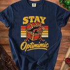 Navy t-shirt with vintage "STAY Optimimic" text and a monster treasure chest graphic.