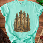 Teal t-shirt with illustration of figures in a redwood forest with a smiling tree.