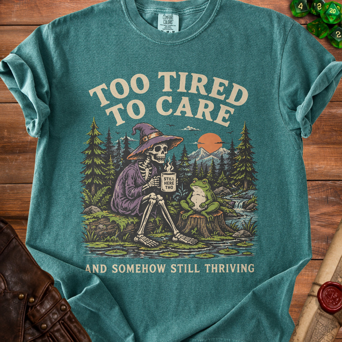 Skeleton in witch hat sits with a frog, text "Too tired to care and somehow still thriving".