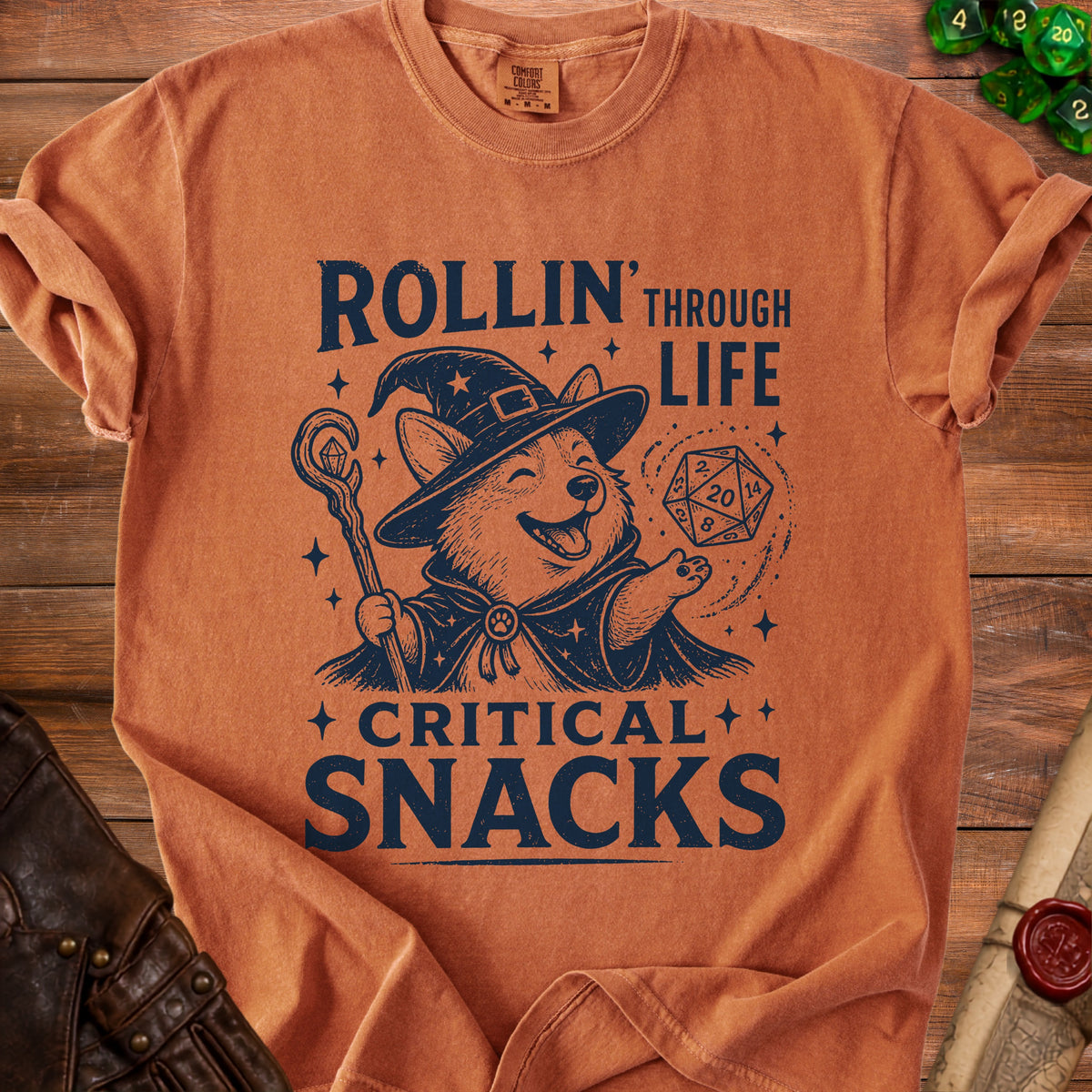 Orange t-shirt with a corgi wizard, d20 die, and text "Rollin' Through Life Critical Snacks".