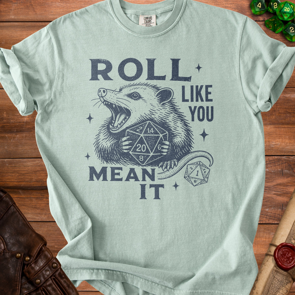 Light blue t-shirt with possum holding dice and text "ROLL LIKE YOU MEAN IT".