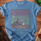 Blue t-shirt with wizard by campfire graphic and text "NOT IGNORING YOU. JUST RECHARGING MY SOCIAL BATTERY."