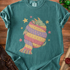 Green t-shirt with cartoon dragon wrapped in striped scarf and surrounded by stars.