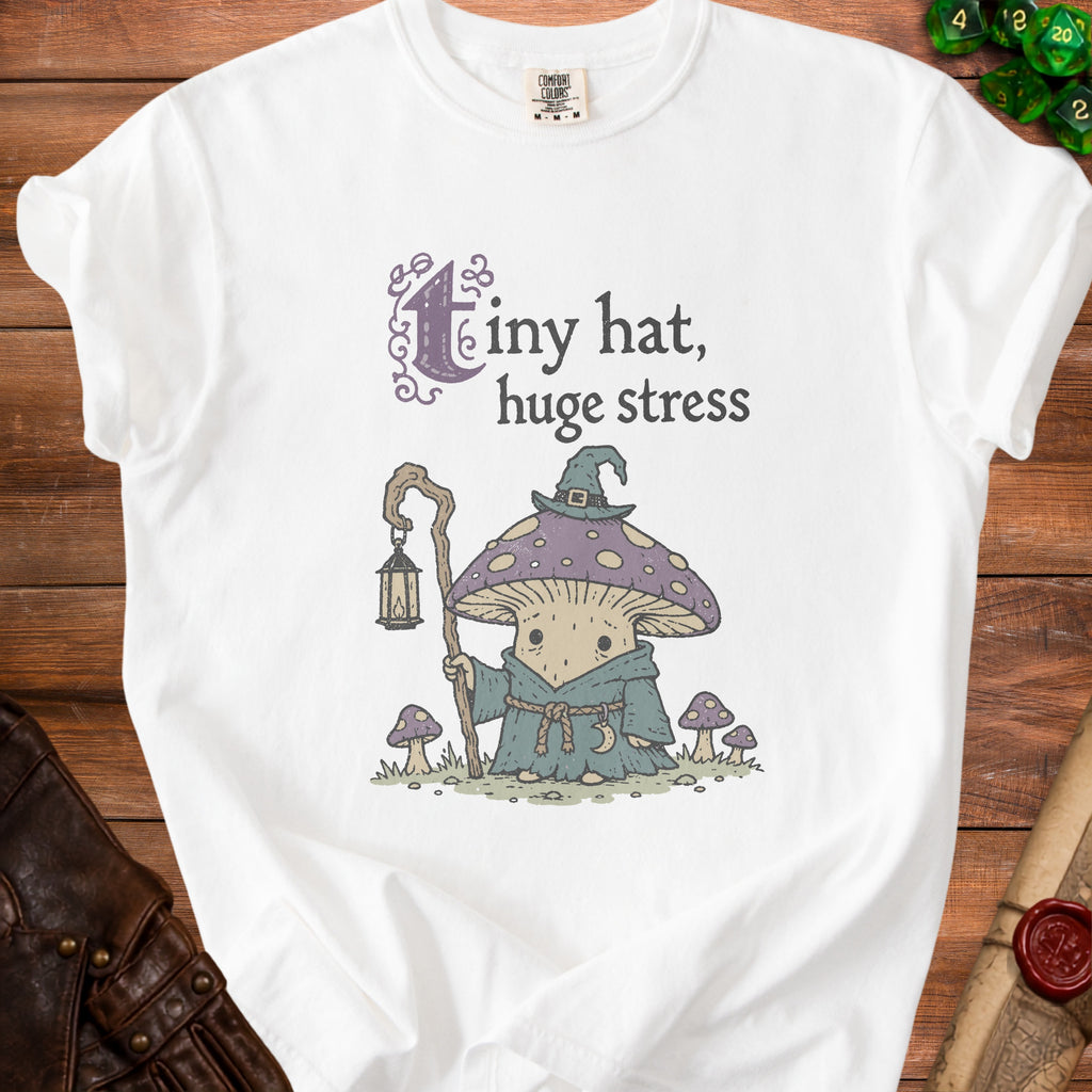 White t-shirt with graphic of mushroom wizard and text "Tiny hat, huge stress".