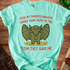 Mint t-shirt with winged creature graphic and text "wish my parents would've added some nepo to the tism they gave me".