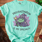 Aqua t-shirt with frog wizard graphic and text "Procrastination is my specialty".