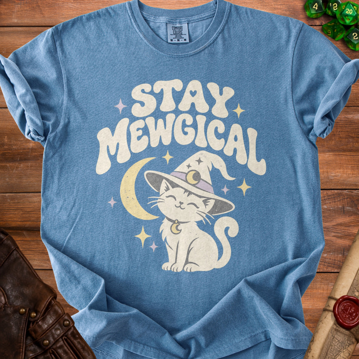 Blue t-shirt with white text "STAY MEWGICAL" and a cartoon cat wearing a witch hat.