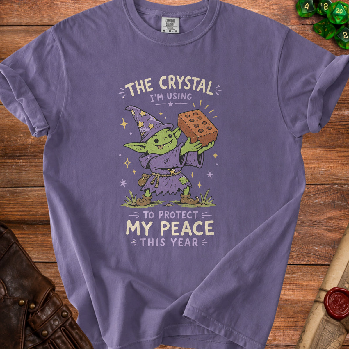 Purple t-shirt with a goblin wizard holding a brick, text reads "The crystal I'm using to protect my peace this year."
