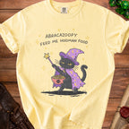 Yellow t-shirt with a cartoon black cat wizard holding spaghetti and meatballs.