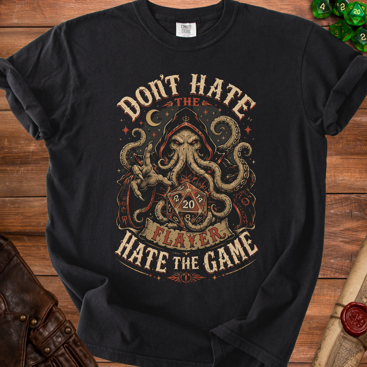 Black t-shirt with a graphic of a hooded creature, dice, and text "Don't Hate the Flayer, Hate the Game".