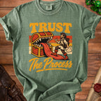 Green t-shirt with "TRUST The Process" text and illustration of a treasure chest.