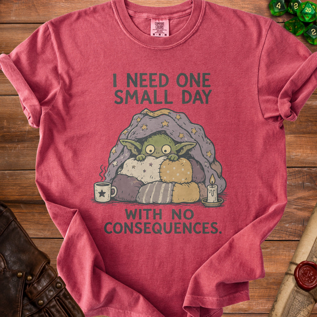 T-shirt with a creature under a blanket and text: I NEED ONE SMALL DAY WITH NO CONSEQUENCES.