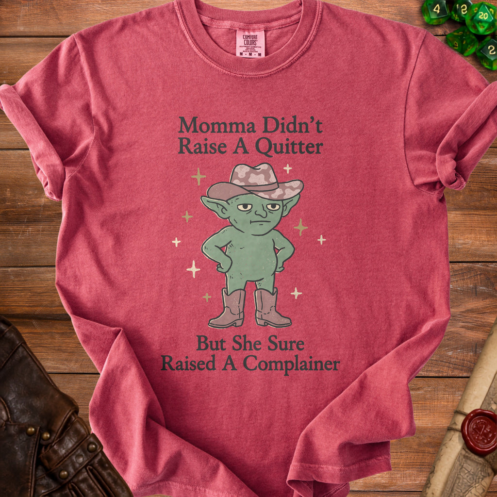 T-shirt with graphic of a goblin in cowboy hat and boots and text "Momma Didn't Raise A Quitter But She Sure Raised A Complainer".