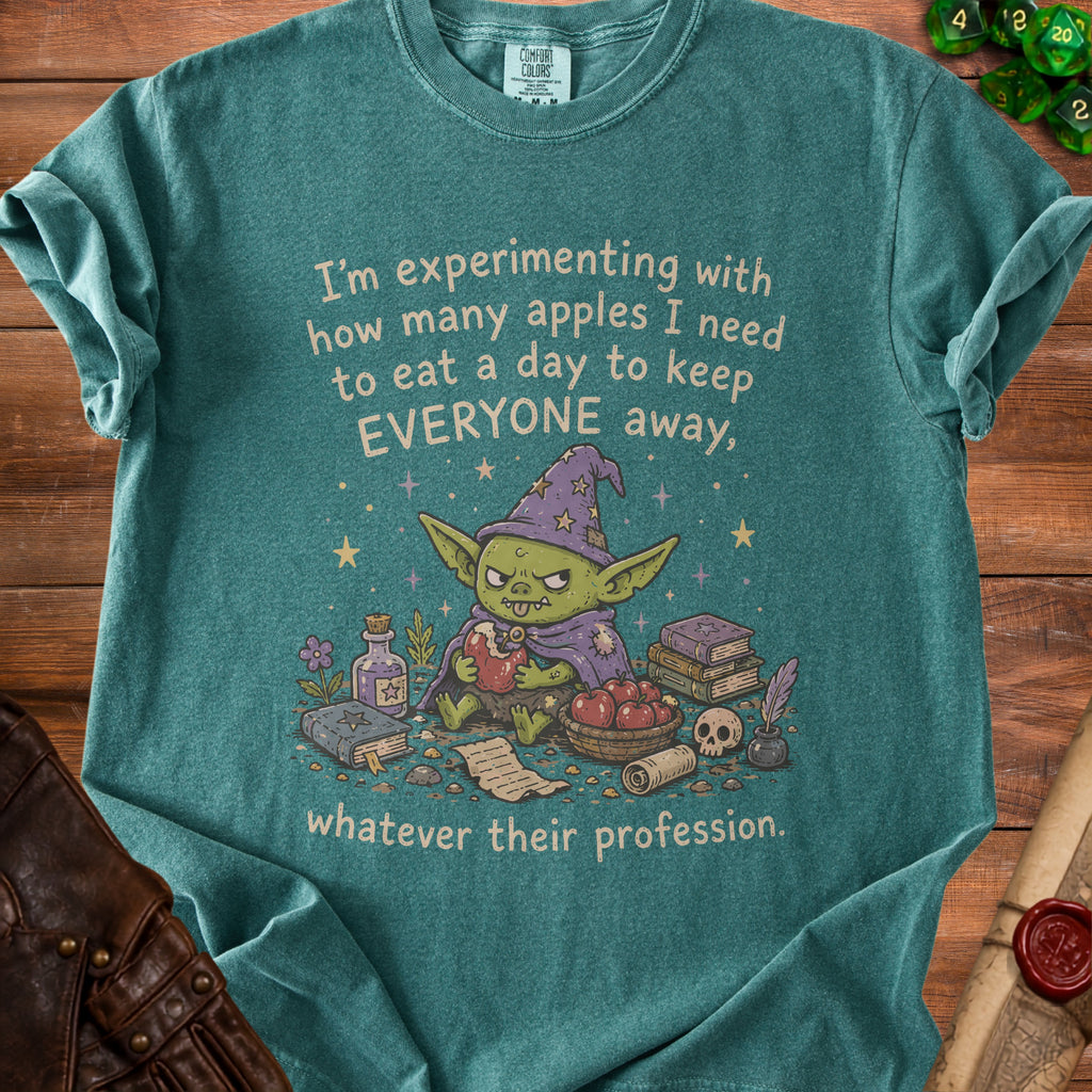 Green t-shirt with a goblin wizard graphic and the text "I'm experimenting with how many apples I need to eat a day to keep EVERYONE away, whatever their profession."