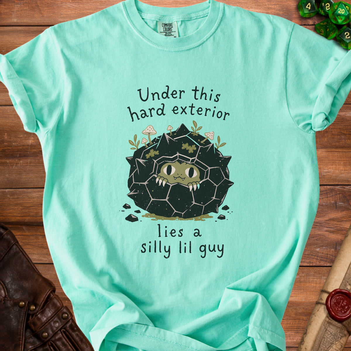Aqua t-shirt with "Under this hard exterior lies a silly lil guy" text and illustration.