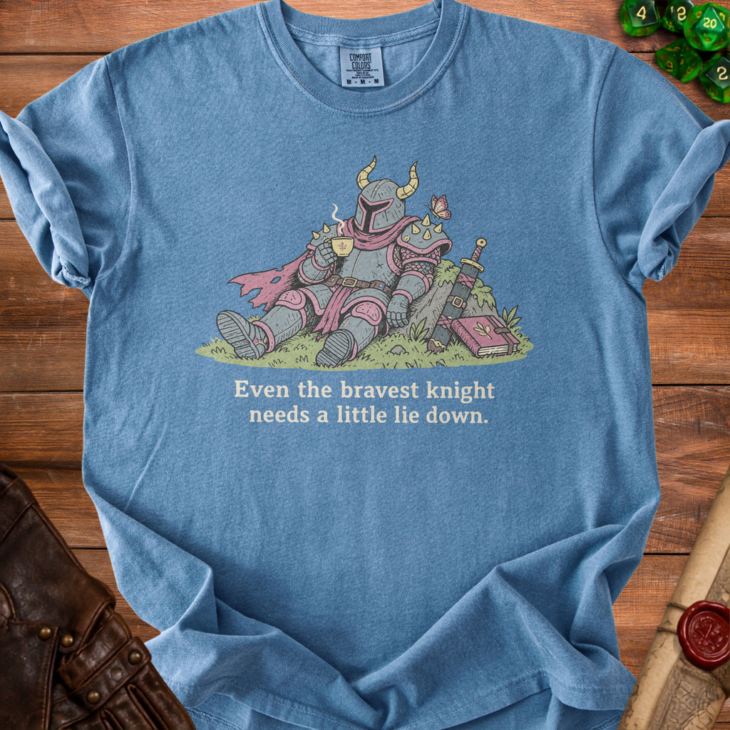 Blue t-shirt with illustration of knight drinking coffee and the text "Even the bravest knight needs a little lie down."