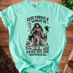 Teal t-shirt with graphic of a witch and black cat, text reads "GOD FORBID A WOMAN BE WEIRD HOT AND WHIMSICAL."