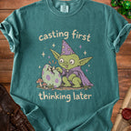 Green t-shirt with illustration of a goblin hatching a speckled egg, "casting first thinking later".