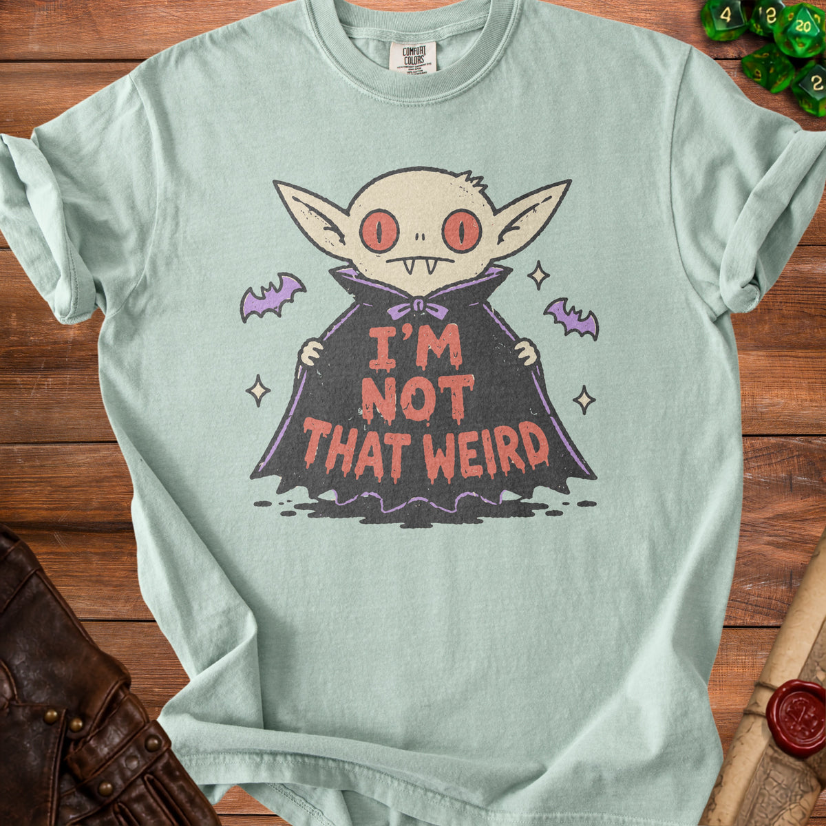 Light green t-shirt with a cartoon vampire graphic and "I'M NOT THAT WEIRD" text.