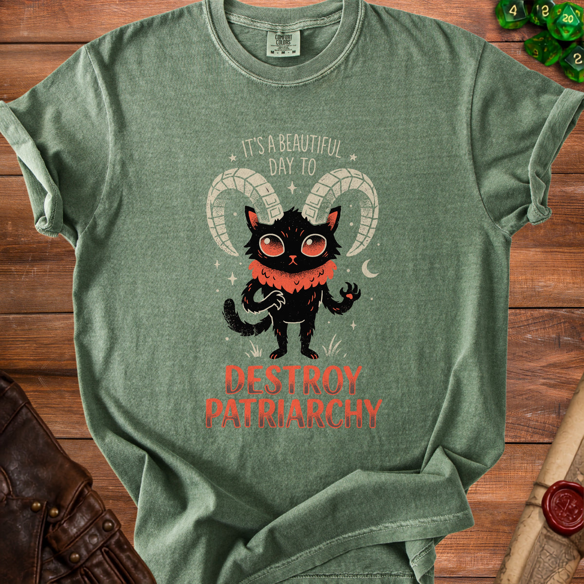 Green t-shirt with black cat graphic, ram horns, and text "It's a beautiful day to destroy patriarchy".