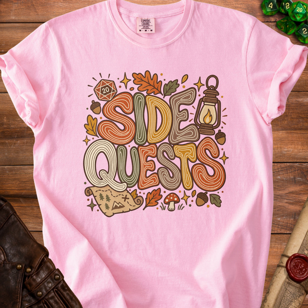 Pink t-shirt with "Side Quests" graphic featuring dice, lantern, map, and fall leaves.