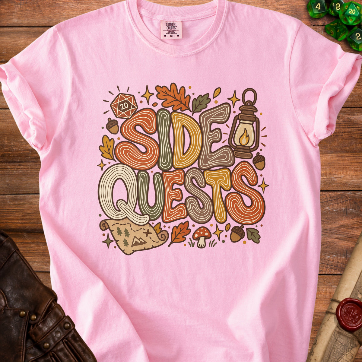 Pink t-shirt with "Side Quests" graphic featuring dice, lantern, map, and fall leaves.
