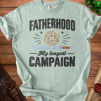 Sage green t-shirt featuring distressed text reading Fatherhood My Longest Campaign with an RPG die and sword.