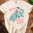 Skeleton cowboy riding a turquoise dragon with text "NOT MY FIRST CURSE"