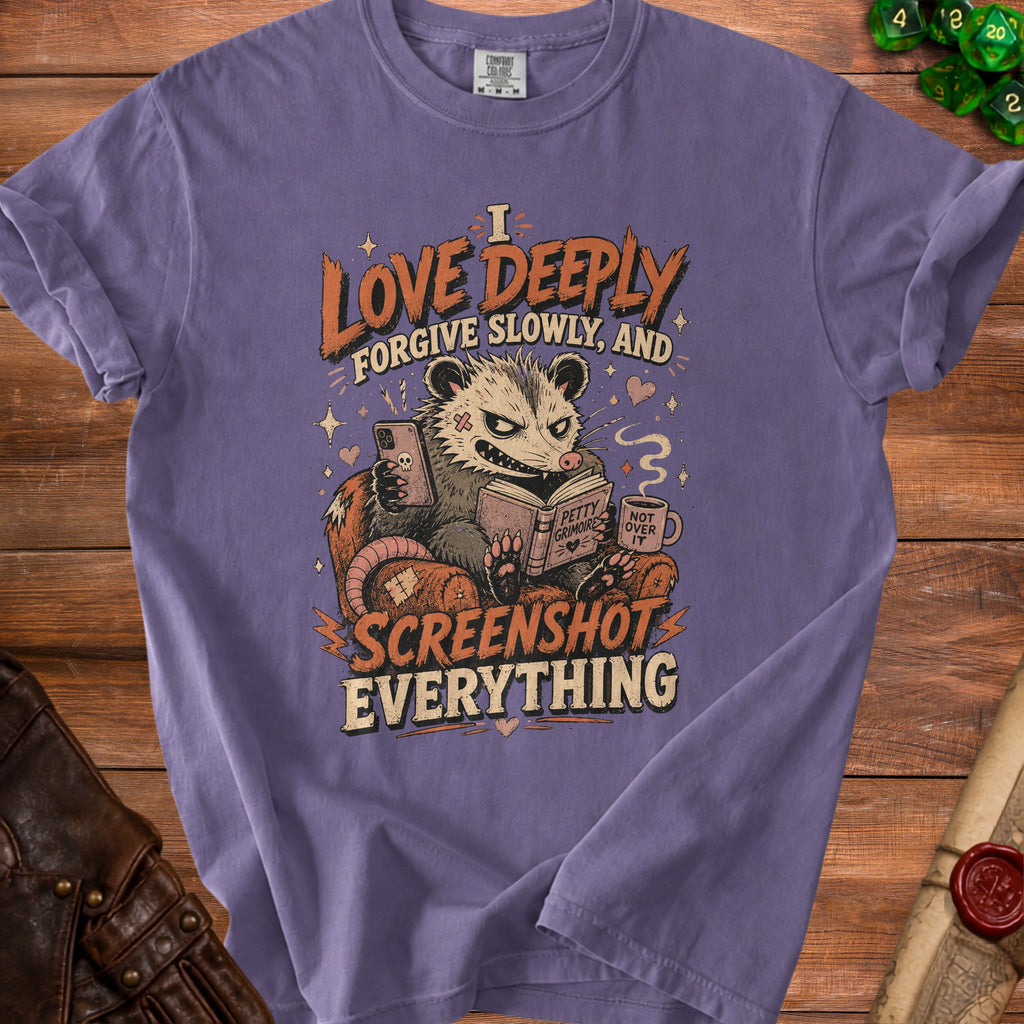 Purple t-shirt with possum reading a book and holding phone, text says "I love deeply forgive slowly, and screenshot everything".