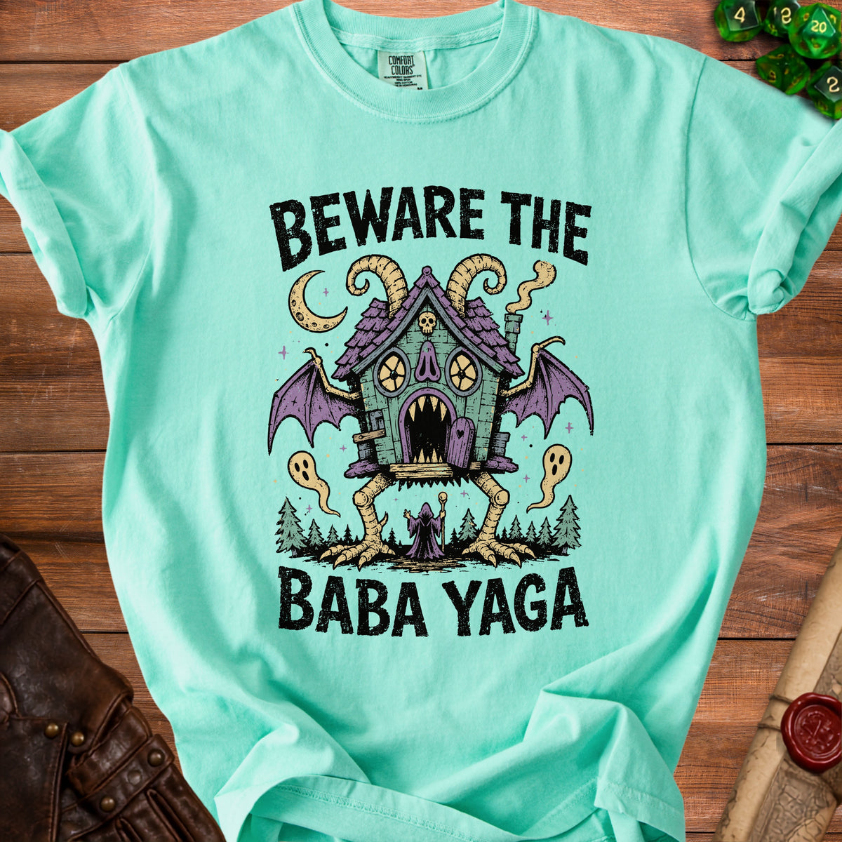 Mint t-shirt with "Beware the Baba Yaga" text and a spooky house illustration.