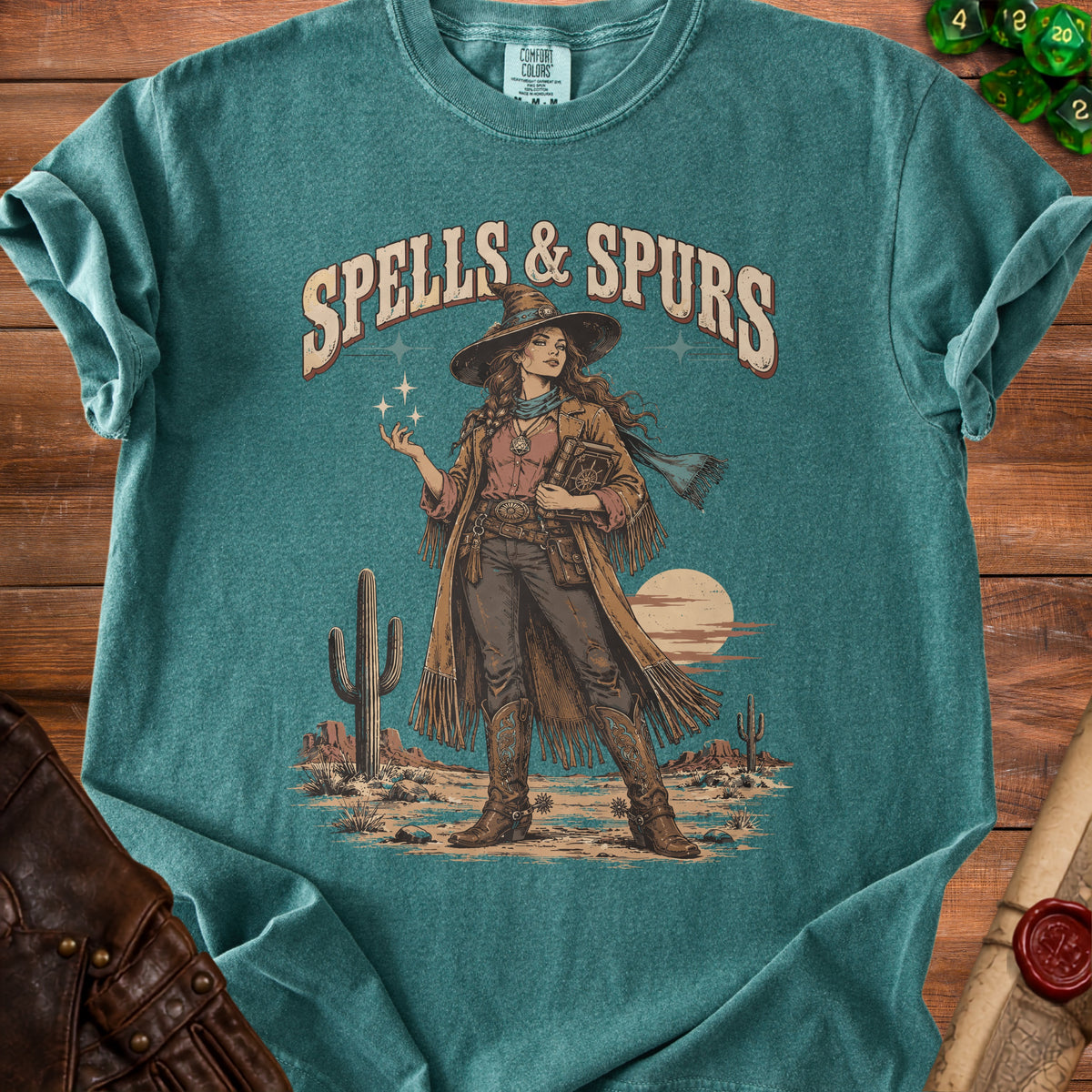 T-shirt graphic with "Spells & Spurs" text and desert scene featuring a witch.