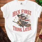 White t-shirt with vintage witch riding broom, "Hex First Think Later" text.