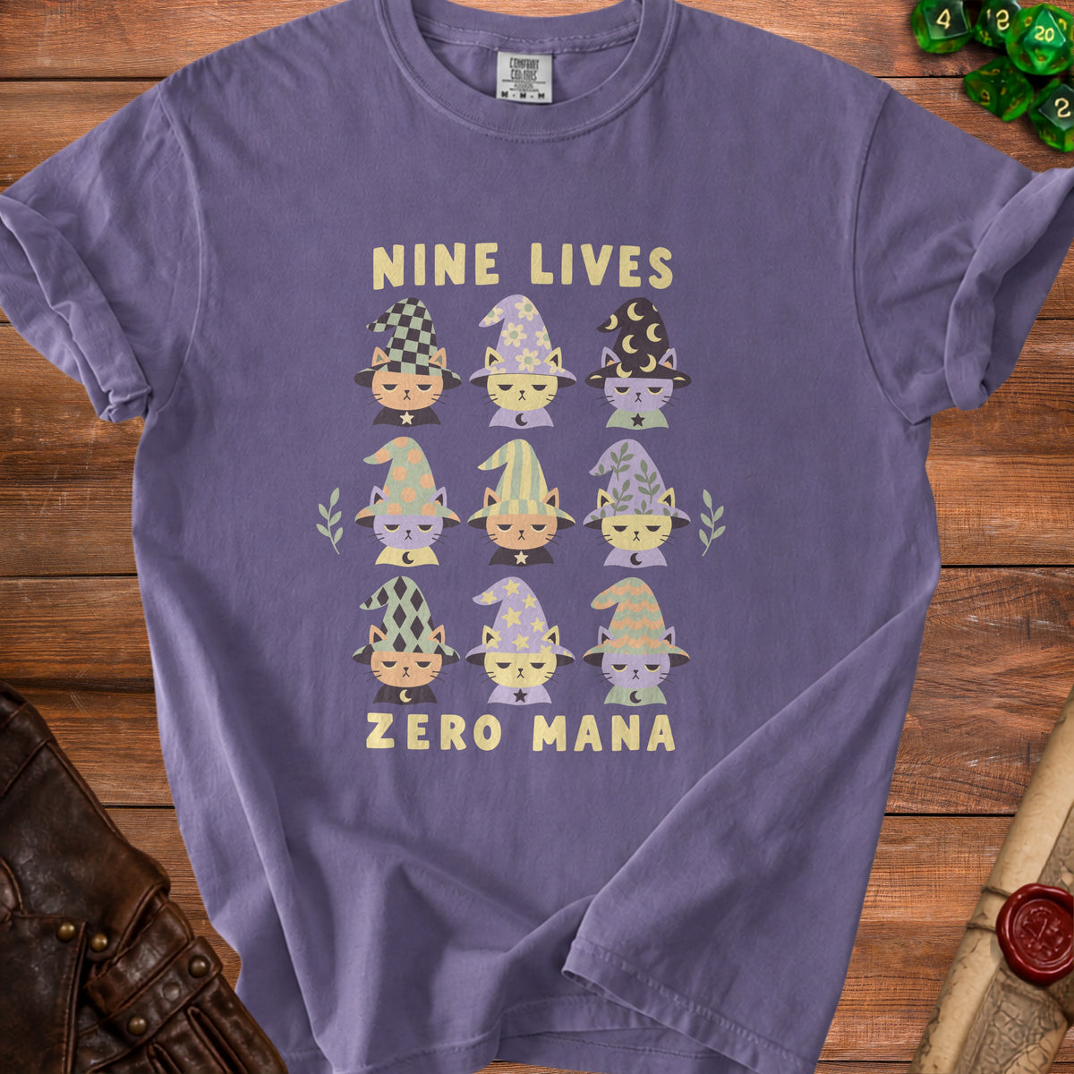 Purple t-shirt with nine cartoon cats wearing wizard hats and the text "NINE LIVES ZERO MANA".