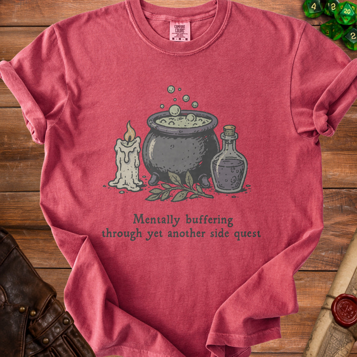 Red t-shirt with cauldron, candle, potion, and text "Mentally buffering through yet another side quest."