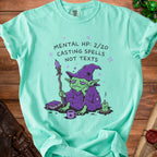 Mint green t-shirt with a bored wizard graphic and "MENTAL HP: 2/20 CASTING SPELLS NOT TEXTS" text.