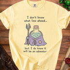 Yellow t-shirt with cartoon wizard, potion, and text "I don't know what lies ahead... but I do know it will be an adventur".
