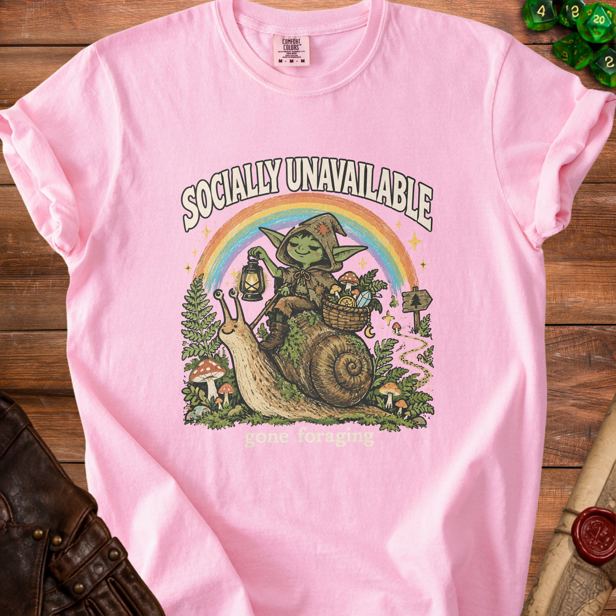 Pink t-shirt with "Socially Unavailable Gone Foraging" graphic of a goblin on a snail.