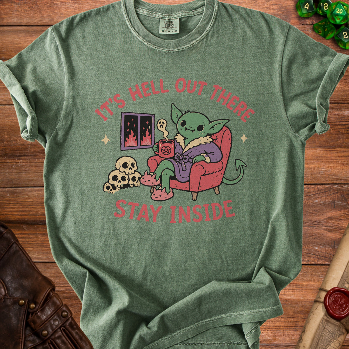 Green t-shirt with a goblin holding coffee, skulls, and text "It's hell out there stay inside".