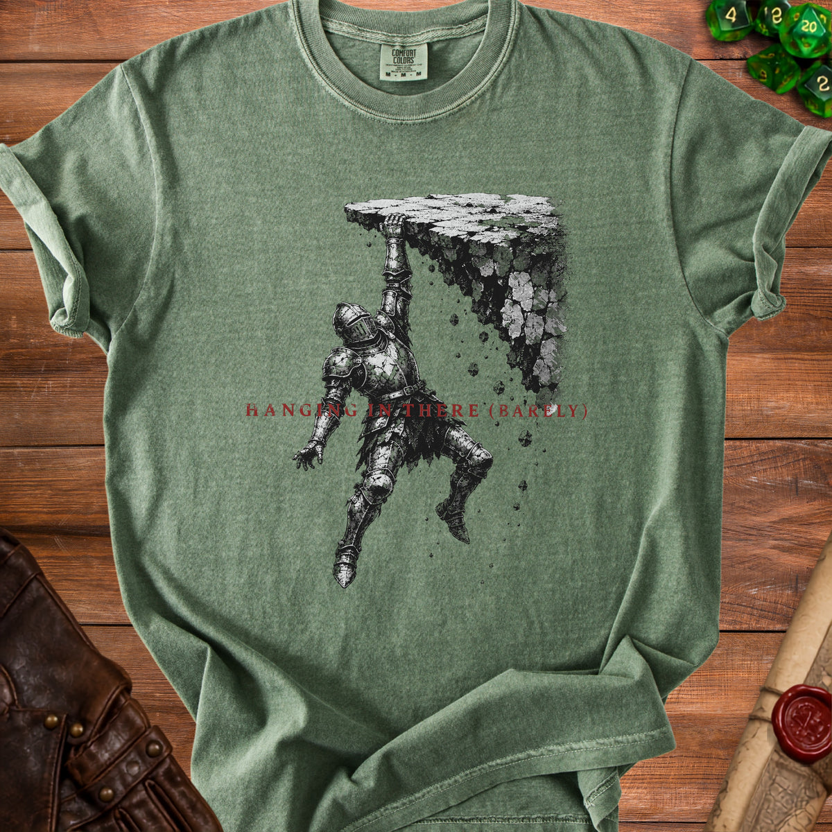 Green t-shirt with knight design and text "HANGING IN THERE (BARELY)".