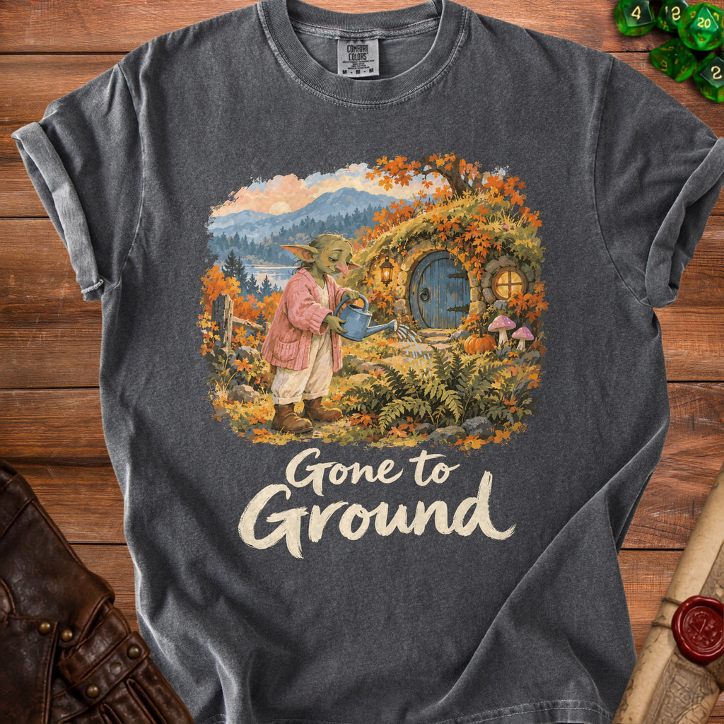 Dark gray t-shirt with a fantasy illustration of a hobbit watering plants and "Gone to Ground" text.